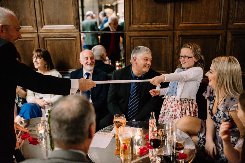 Guests reacting with laughter during an interactive wedding magic routine.