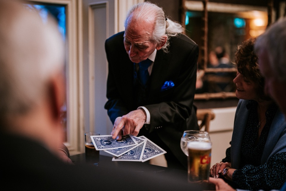 Live card magic performance with wedding guests seated at a table.