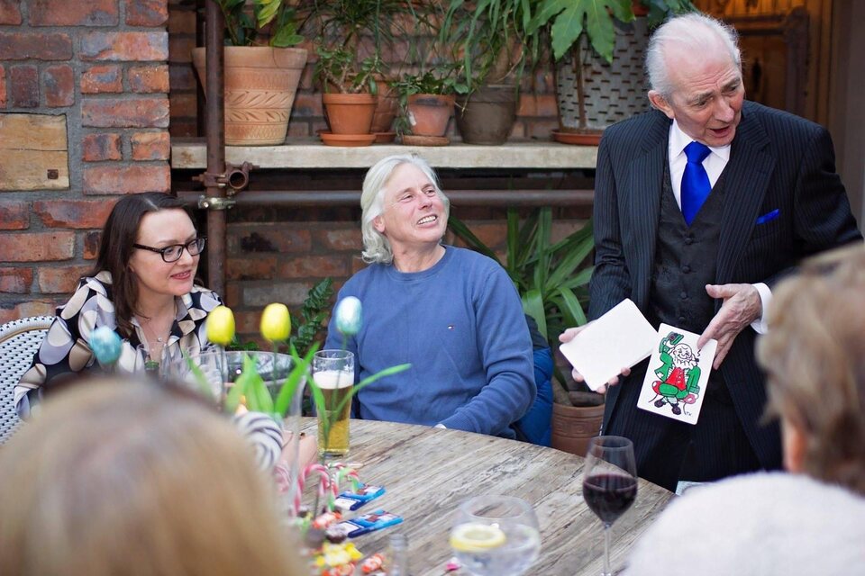 Pat Fallon performing close-up magic for guests around a wedding table.